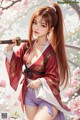 Woman in traditional attire holding a sword amidst cherry blossoms.