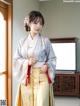 A woman in a kimono standing in front of a window.