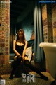 A woman sitting on a bed in a bathroom next to a bathtub.