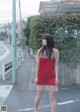 A woman in a red dress is standing on the street.