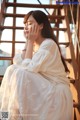 A woman in a white dress sitting on a stairway.