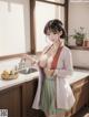 A woman in a kitchen with a bowl of fruit on the counter.