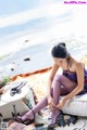 A woman sitting on top of a bed next to the ocean.