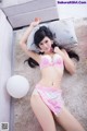 A woman in a pink and white lingerie laying on a couch.