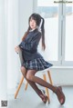 A woman in a school uniform sitting on a chair.