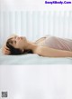 A woman laying on a bed with her head on her hands.