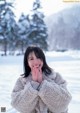 A woman in a white coat standing in the snow.