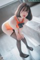 A woman in an orange bodysuit and black stockings posing for a picture.