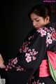 A woman wearing a black and pink kimono with pink flowers.