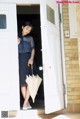 A woman standing in the doorway of a house holding an umbrella.